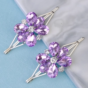 Macro detail of silver hair pins with purple crystal petals and shimmering center stones