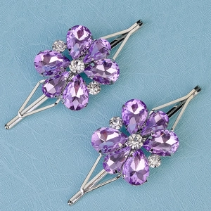 Detail view of two purple crystal flower hair clips with sparkling stones and silver plating