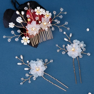 Detailed shot of handmade pearl flower hair comb set with crystals on a navy background