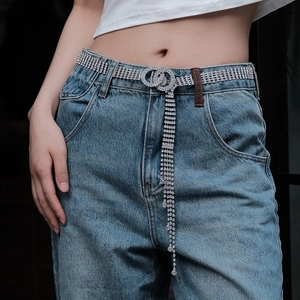 Dettaglio della cintura in strass argento con doppi anelli e frange lunghe su jeans