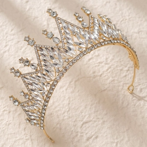 Macro detail of luxury gold bridal tiara with marquise crystals on beige texture