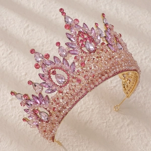 Detailed close-up of luxury bridal crown with pink crystals and intricate gold beadwork
