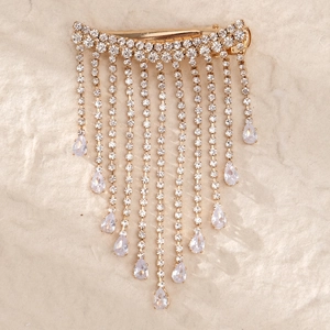 Detail of gold bow hair clip with dangling rhinestone tassels and pear-cut crystal drops