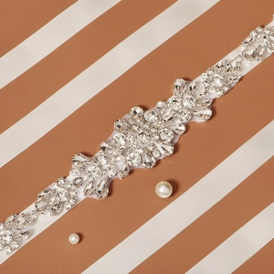 Detailed view of bridal belt with intricate rhinestone flower patterns on white ribbon