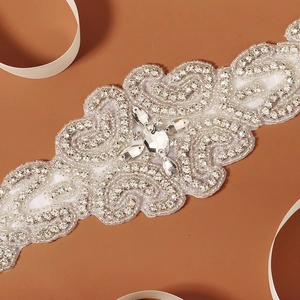 Macro detail of bridal sash showing intricate hand-sewn rhinestones and sparkling crystals