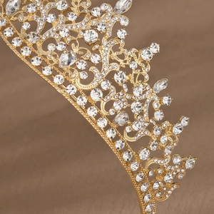 Close-up of golden bridal tiara featuring intricate Baroque scrollwork and sparkling crystals