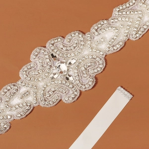 Macro detail of luxury bridal sash with silver beads and shimmering crystals on white satin