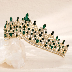 Detailed close-up of a vintage gold crown with emerald crystals and white rhinestones