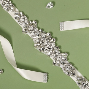Elegant bridal sash belt with sparkling rhinestones and white satin ribbon on olive background