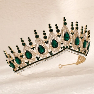 Detailed close-up of golden baroque tiara with green crystal teardrops and white rhinestones