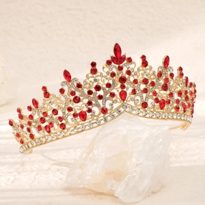 Detailed view of luxury bridal crown with red crystals and gold filigree on white stone