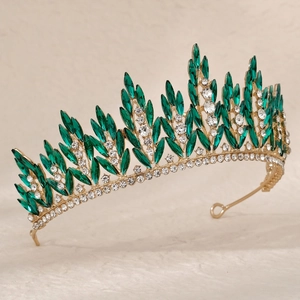 Close-up of golden crown with marquise green gemstones and sparkling clear rhinestones