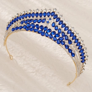 Détail de couronne de mariée dorée avec gemmes bleu saphir et cristaux sur fond de fourrure