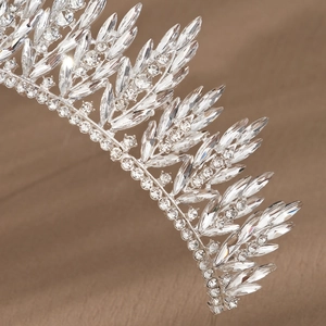 Detailed macro shot of bridal crystal crown with marquise-cut rhinestones on champagne silk