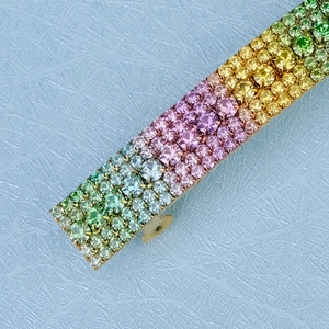 Close-up of rainbow crystal rhinestones on a gold hair clip with gradient color stones
