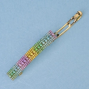 Close-up of golden hair clip with rainbow gradient rhinestones on blue background