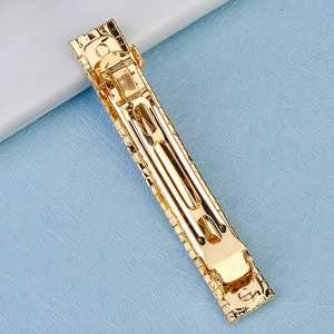 Close-up of golden alloy spring hair clip showing detailed geometric texture and metallic finish