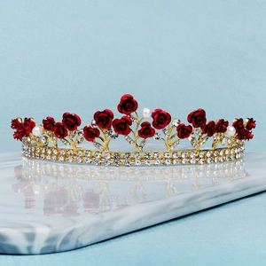 Elegante goldene Krone mit roten Rosen und weißen Kristallen für Hochzeiten auf Marmor