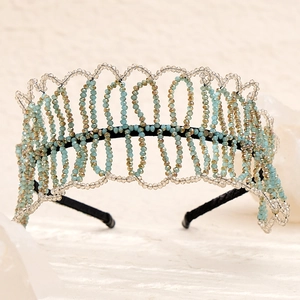 Close-up of handmade crystal beaded headband with light blue and gold wave pattern