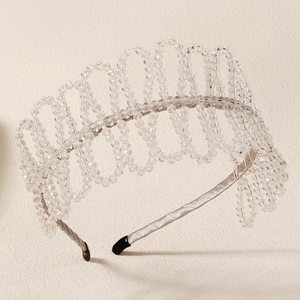 Macro view of crystal beaded headband with silver wave design and satin texture finish