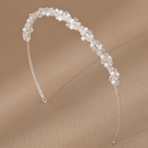 Close-up of bridal headband with intricate white pearls and clear crystal beads on silver wire
