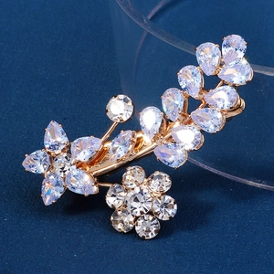 Détail d'une pince à cheveux fleurie dorée avec zircons brillants sur fond bleu foncé