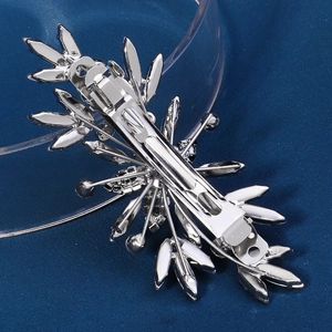 Détail d'une pince à cheveux fleur argentée avec cristaux brillants sur velours bleu