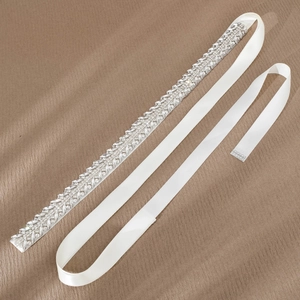 Close-up of elegant leaf-patterned silver rhinestones on a white satin bridal belt