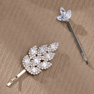 Détail de barrettes argentées avec zircons marquise sur fond en cuir marron élégant