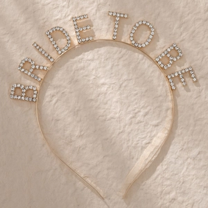 Detail of Bride To Be lettering decorated with white rhinestones on a gold metal headband