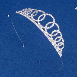 Close-up of a silver tiara crown with sparkling rhinestones on a textured blue fabric