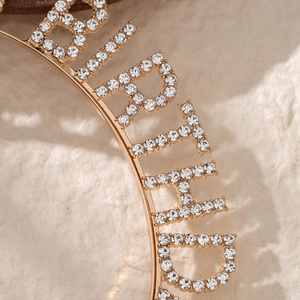 Macro shot of gold-plated bridal headband featuring sparkling rhinestone BRIDE lettering