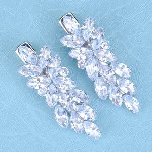 Vue détaillée des boucles d'oreilles en forme de feuille avec zircons sur tissu bleu