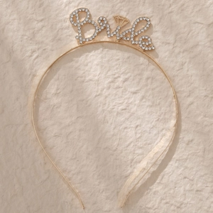 Détail d'un serre-tête Bride doré avec strass scintillants et une icône de bague