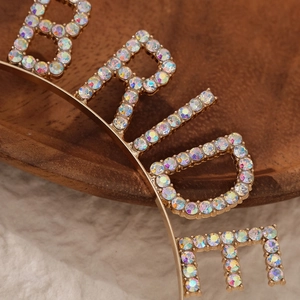 Macro shot of gold bridal headband featuring multi-color rhinestones spelling BRIDE