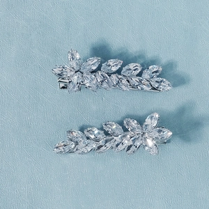 Gros plan de deux pinces à cheveux argentées avec pierres de zircon en forme de feuilles