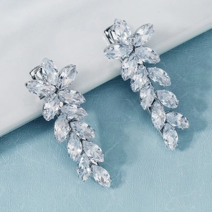 Détail de boucles d'oreilles élégantes en zircon avec monture argentée en forme de feuille