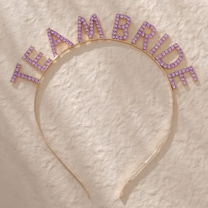 Detailed view of Team Bride headband with purple rhinestones on a gold metal frame