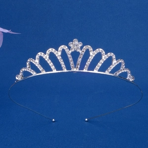 Macro shot of silver rhinestone crown headband with floral pattern on blue background