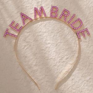 Detail shot of Team Bride headband with pink rhinestones on a gold metal frame
