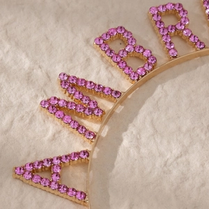 Macro view of gold headband featuring pink rhinestones set in birthday themed letters