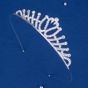Detailed view of silver crystal tiara with sparkling rhinestones on deep blue background