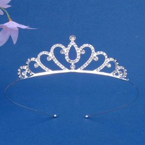 Detailed view of silver rhinestone princess tiara crown with heart motifs on blue background