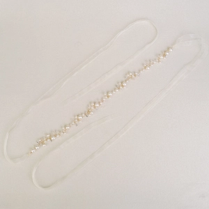 Detail of bridal sash with white organza ribbon and pearl rhinestone vine decoration