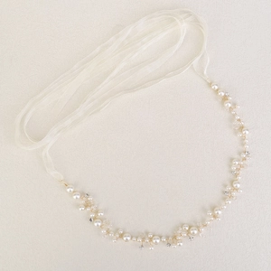 Macro shot of handmade bridal headband with white pearls and clear crystals on gold wire