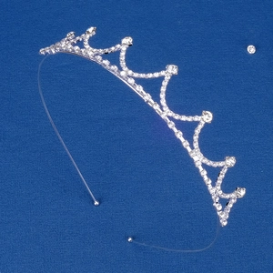 Close-up of silver princess crown with sparkling rhinestones on blue textured fabric