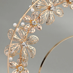 Detail of golden floral crown with hollow petals, sparkling crystals and white pearls