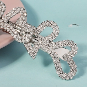 Gros plan d'une pince à cheveux argentée ornée de strass et d'un nœud élégant