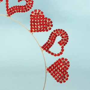 Détail macro des strass rouges en forme de cœur sertis sur un serre-tête en métal doré