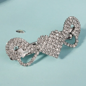 Détail d'une barrette argentée avec strass brillants en forme de cœur et infini